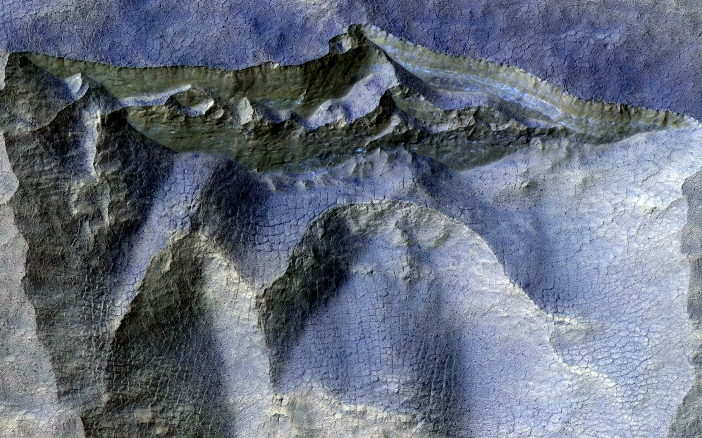 ICY MARS CLIFFS About one-third of Mars has ice just beneath the surface. Scientists study the ice to learn what early Mars was like and whether it was warm and wet long enough for life to take hold. In this false-color image from NASA’s Mars Reconnaissance Orbiter, layers of bluish ice can be seen layered inside an exposed brownish cliff face. MRO takes repeat images of scenes like this, occasionally revealing ice boulders that have tumbled down slopes. NASA / JPL-Caltech / University of Arizona